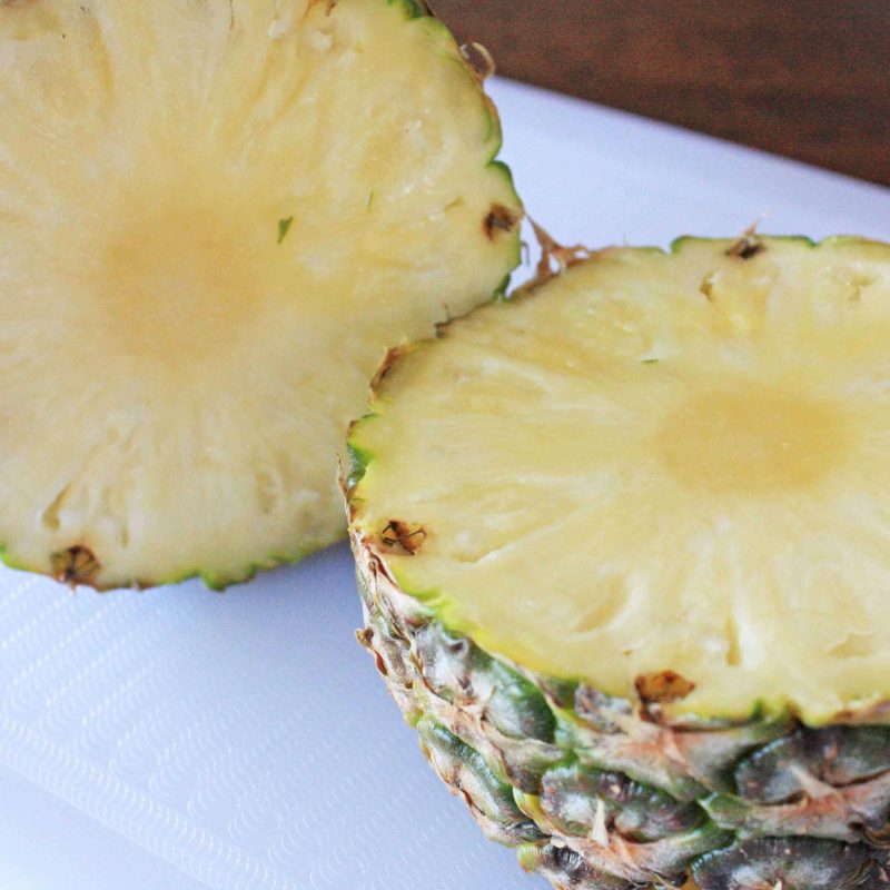 Cut off the top and bottom off your pineapple and then slice in half